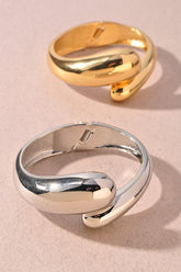 Polished gold metal bangle featuring a modern twist design