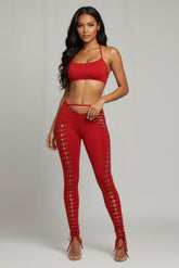 Woman wearing a red outfit with lace-up details on a gray background