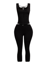 Sleek black tank top with a tie-front detail, paired with fitted capri pants for a modern and edgy outfit.