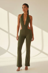 Woman wearing a green jumpsuit standing against a neutral background
