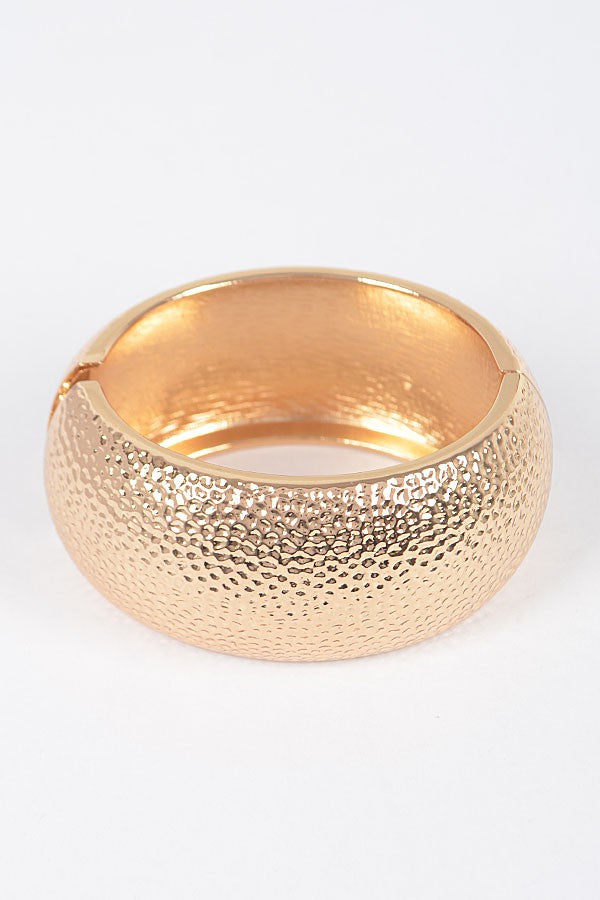 Bold wrist styling with mixed gold bangles in hammered and polished metals

