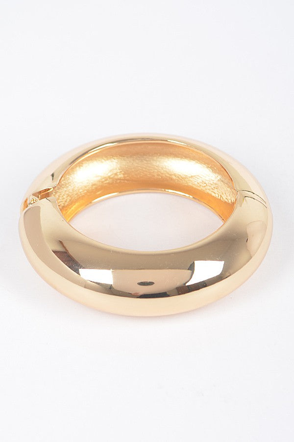 Stacked gold bangles featuring hammered texture and smooth gloss

