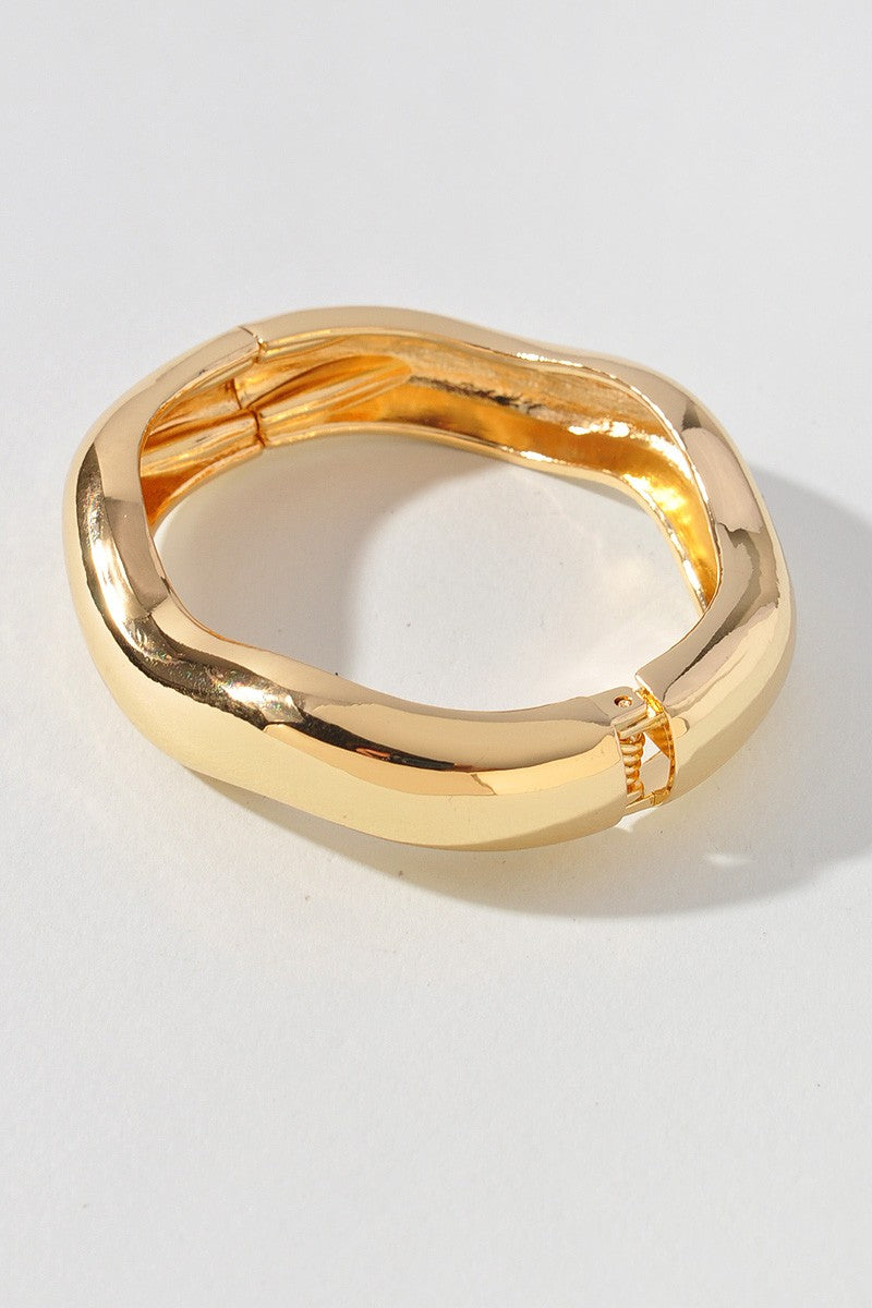 Modern gold-tone bangle featuring spring hinge and bold curved shape

