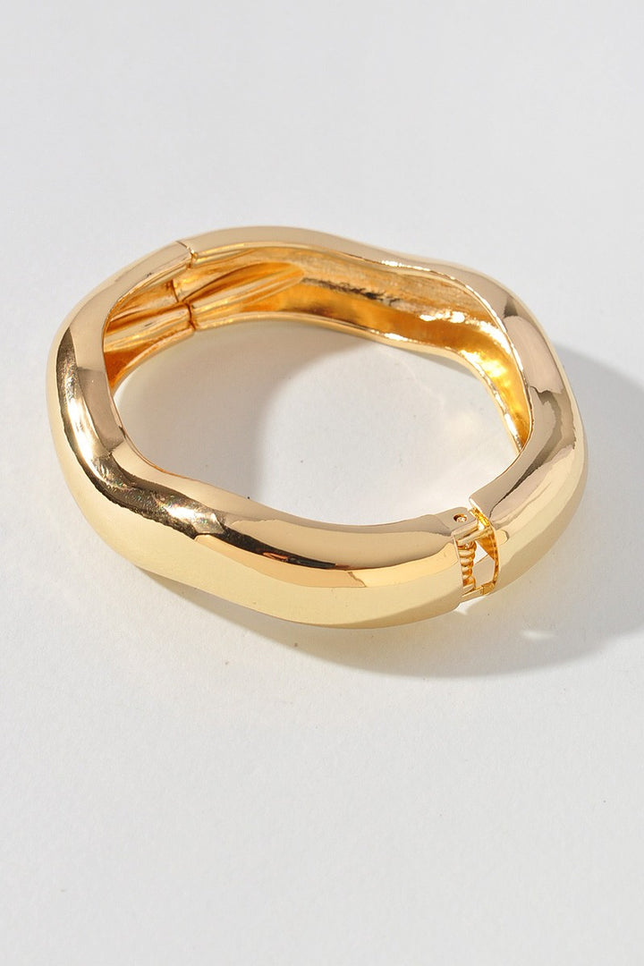 Modern gold-tone bangle featuring spring hinge and bold curved shape


