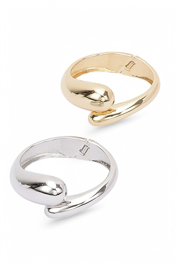 Chunky gold bracelet with fluid shape and glossy reflective surface

