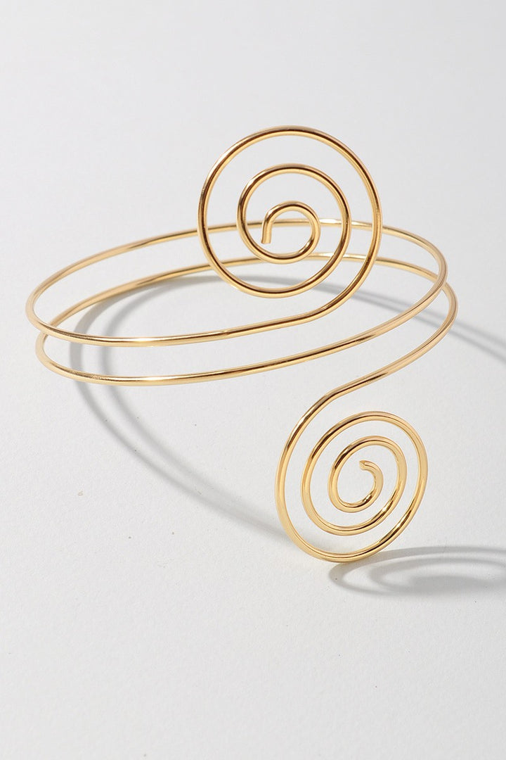 Hypnotic gold arm cuff featuring symmetrical swirl ends and open back

