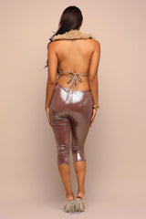 Woman wearing metallic leggings and a strapless top with fur trim on a beige background