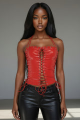 Model wearing a red lace-up top and black leather pants against a neutral background