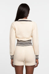 Person wearing a cream-colored outfit with black stripes on a white background