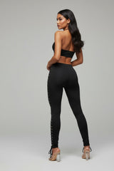 Woman wearing a black outfit with lace-up sides on a gray background