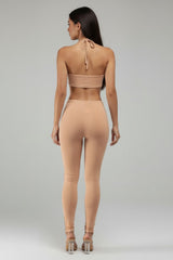 Woman wearing a beige one-piece outfit on a plain background