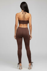 Woman wearing a brown outfit with lace-up details on a gray background