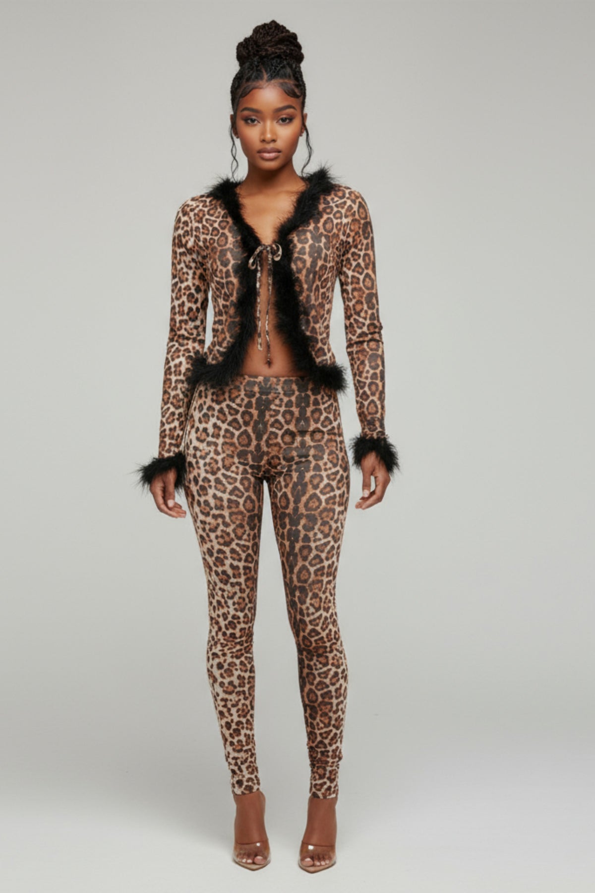 Model wearing a leopard print outfit with black fur trim on a gray background