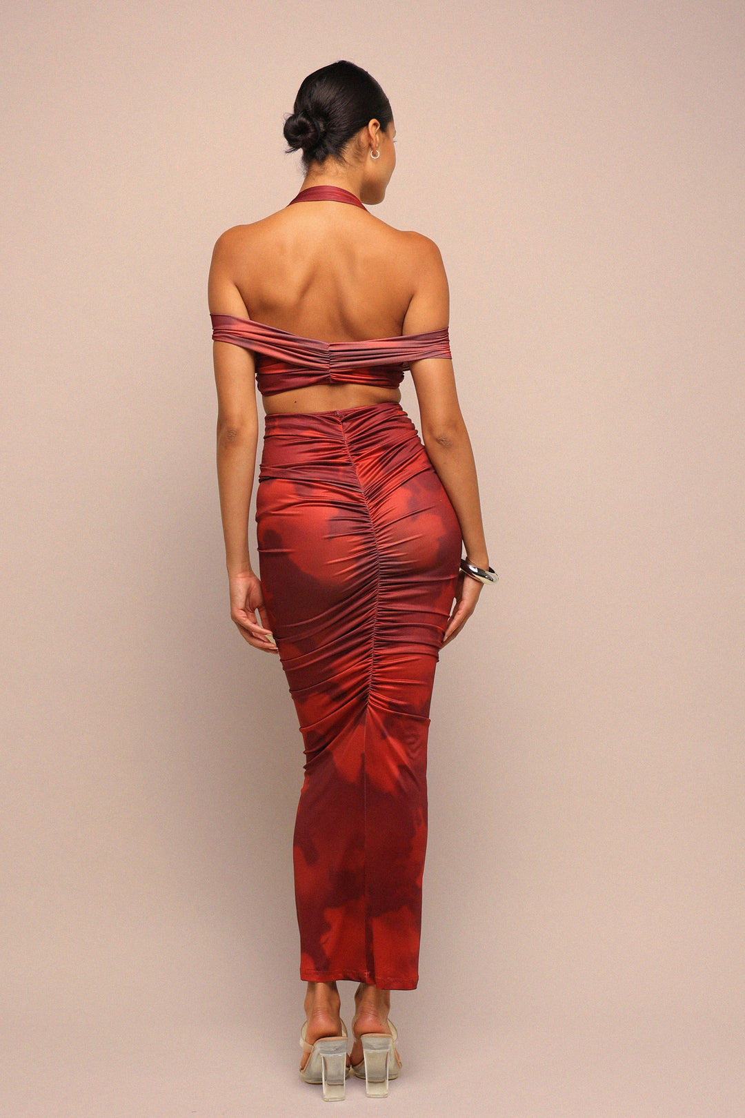 Woman wearing a red off-shoulder dress with ruched details on a beige background