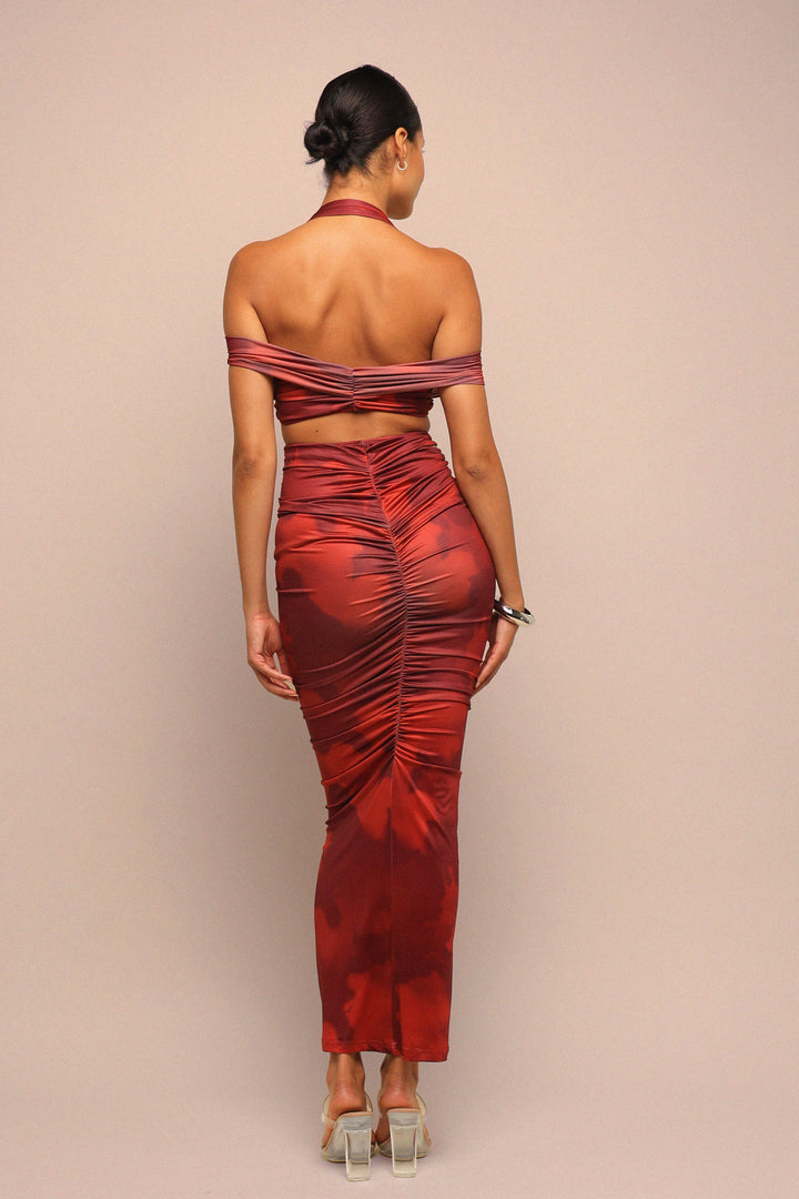 Woman wearing a red off-shoulder dress with ruched details on a beige background