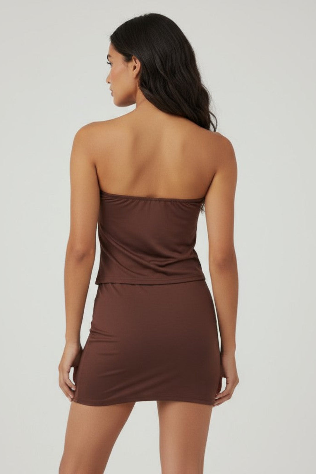 Woman wearing a brown strapless dress on a plain background