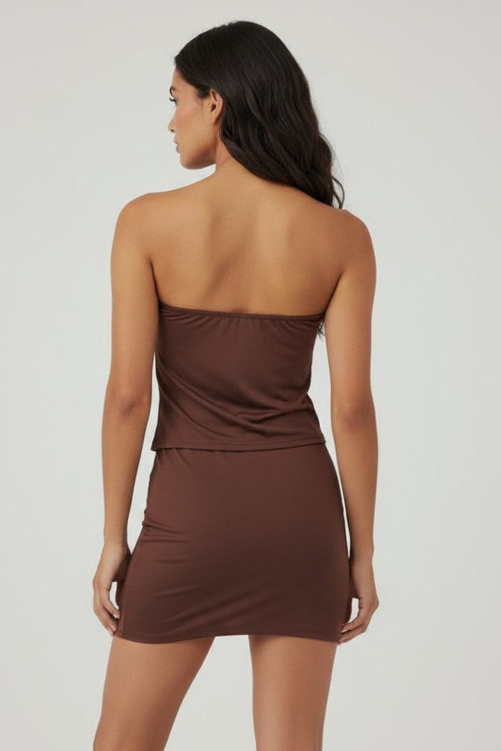 Woman wearing a brown strapless dress on a plain background