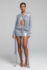 Woman wearing a silver outfit with a sheer overlay on a gray background