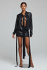 Model wearing a black leather outfit with a long coat and shorts on a white background