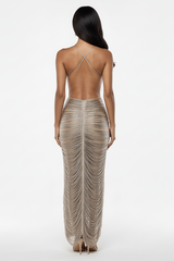 Woman wearing a backless, beige, ruched dress on a white background