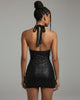 Back view of black lace-printed halter dress with open tie-back design