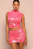 Woman wearing a pink vinyl top and skirt set against a beige background