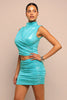 Woman wearing a turquoise dress against a beige background