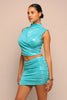 Woman wearing a turquoise dress against a beige background