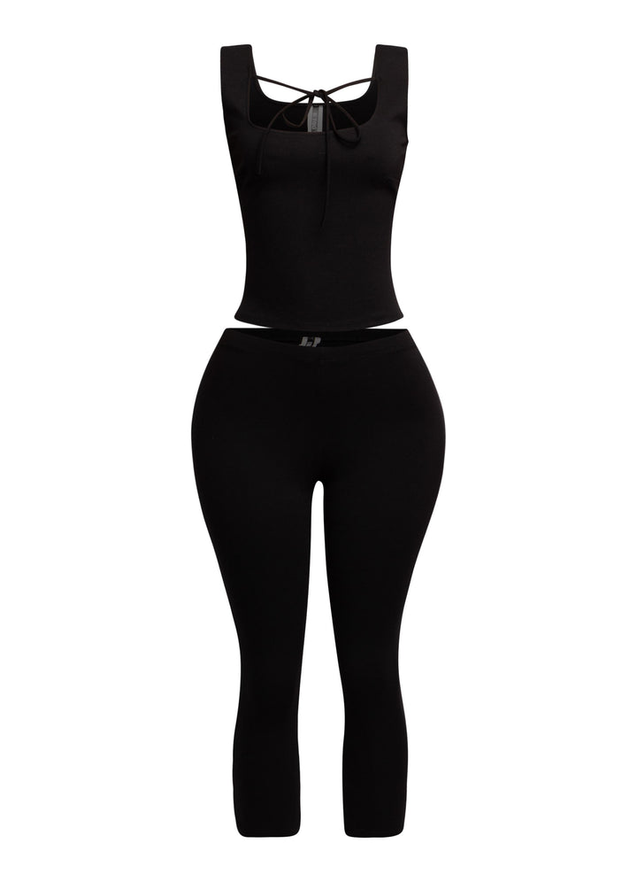 Sleek black tank top with a tie-front detail, paired with fitted capri pants for a modern and edgy outfit.