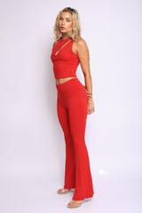 Red two-piece outfit with twisted shoulder detail and wide-leg flare hem for dramatic shape

