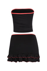 Black bodycon two-piece with neon pink edges, stretchy tube top, and midrise skirt with playful hemline