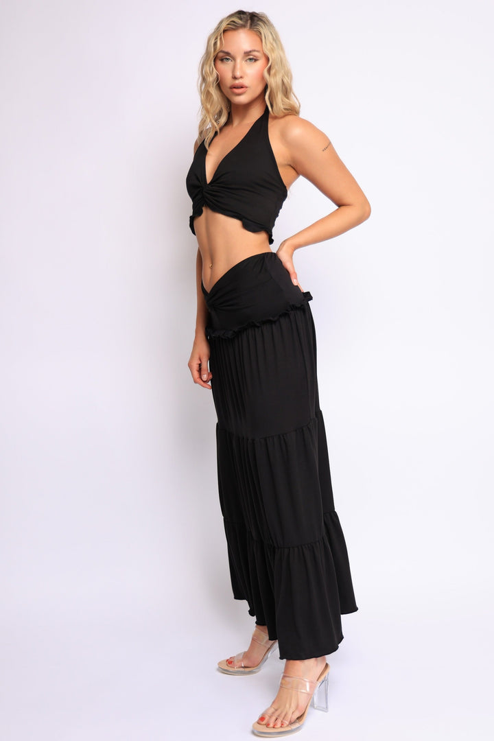 Black halter neck twist-front crop top paired with tiered low-rise maxi skirt


