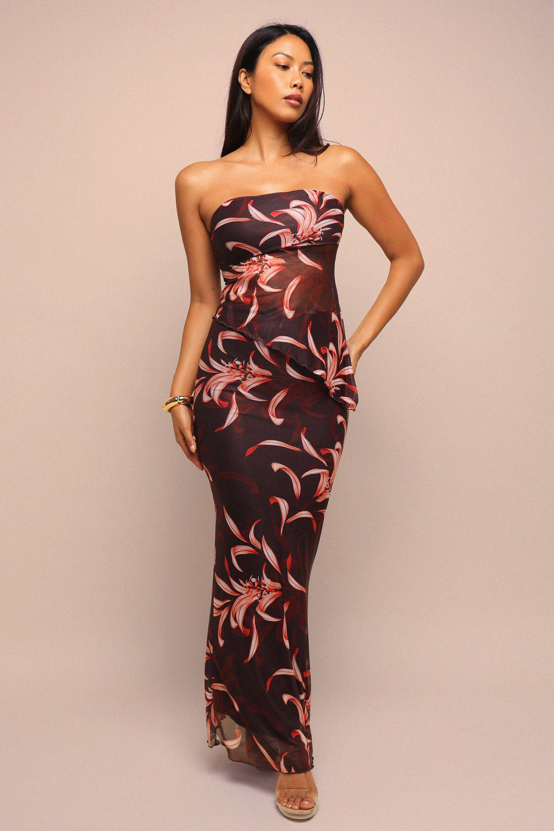 Woman wearing a strapless floral dress against a beige background