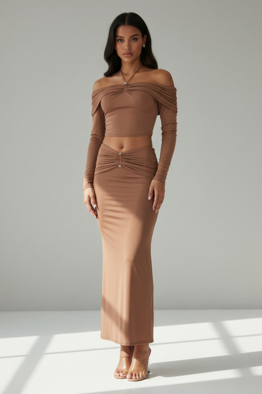 Woman wearing a brown off-shoulder top and skirt set against a plain background