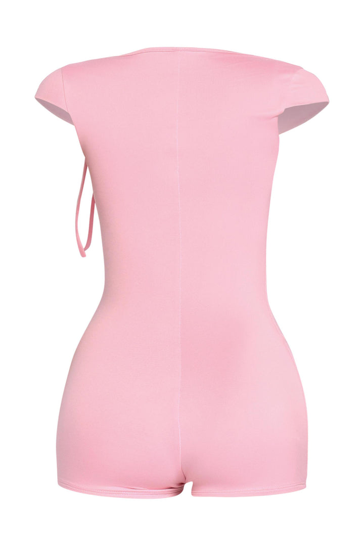Rear view of baby pink cap sleeve romper with tight silhouette and short hem

