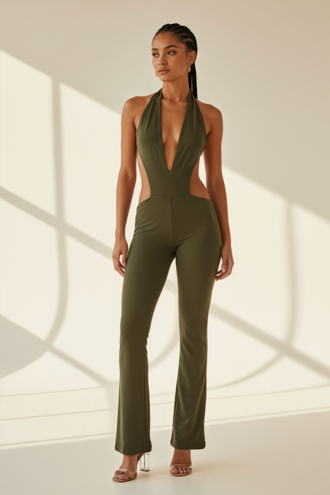 Woman wearing a green jumpsuit with cut-out design in a minimalistic setting
