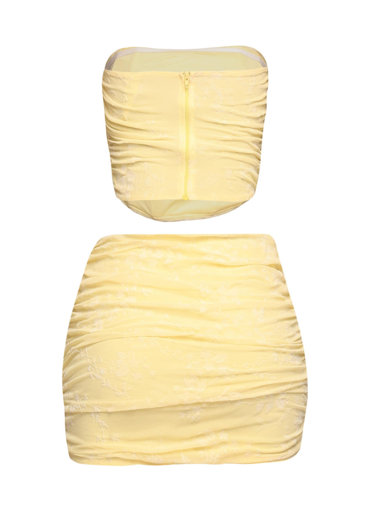 Side view of yellow ruched jacquard tube top and curve-hugging mini skirt

