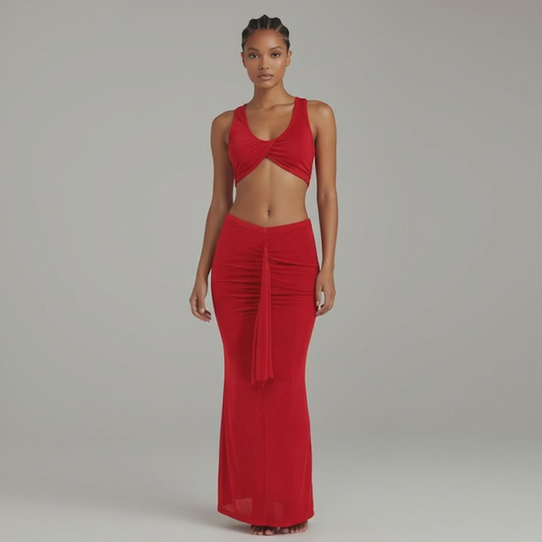 Model walking in red twist front two-piece set with ruched maxi skirt and flared hem, showing curve-hugging silhouette and fluid fabric movement