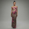 Model walking in strapless leopard print maxi dress with magenta floral accents and flared hem, showcasing curve-hugging silhouette in motion