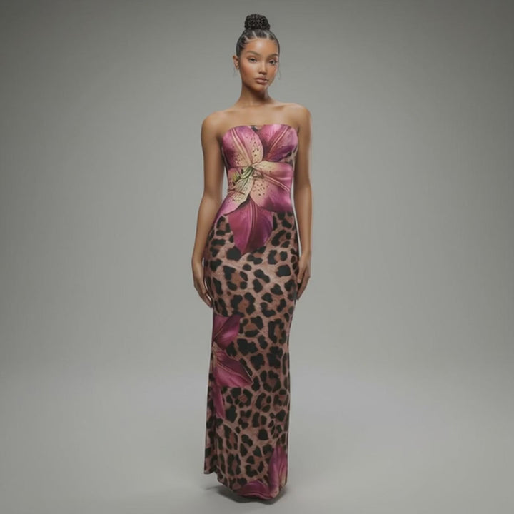 Model walking in strapless leopard print maxi dress with magenta floral accents and flared hem, showcasing curve-hugging silhouette in motion