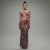 Model walking in strapless leopard print maxi dress with magenta floral accents and flared hem, showcasing curve-hugging silhouette in motion