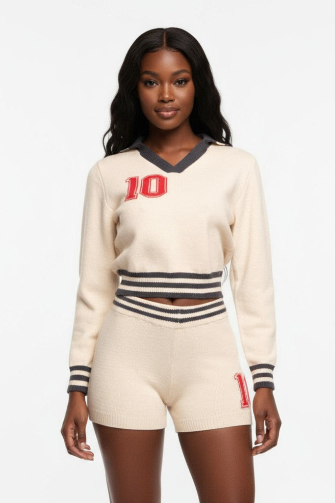 Woman wearing a cream-colored sweater and shorts with black and red accents on a white background