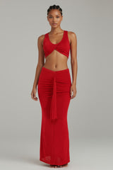Front angled view of red ruched maxi set with twist front top and bold drape detail