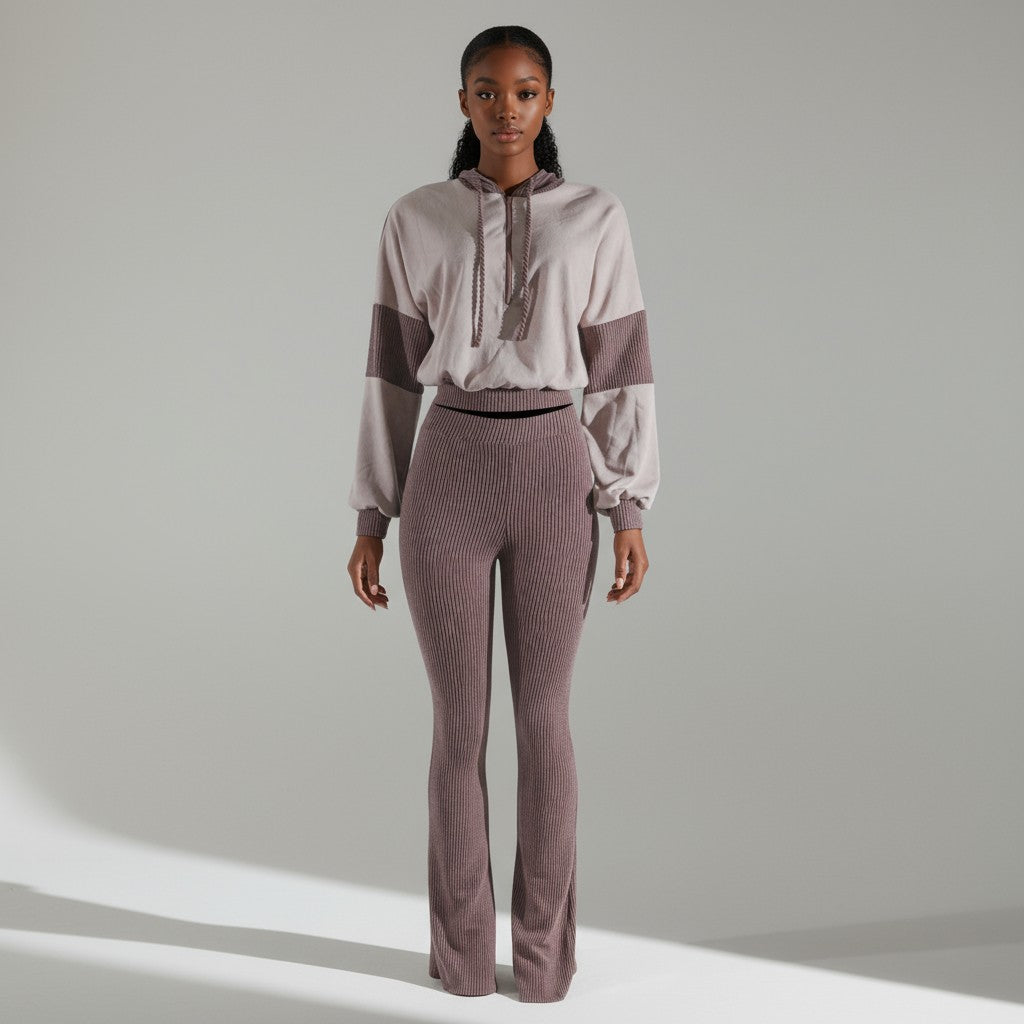 Woman wearing a two-tone outfit with a light top and dark pants on a neutral background