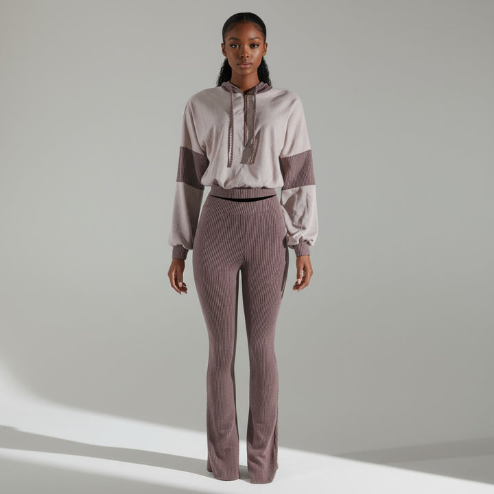 Woman wearing a two-tone outfit with a light top and dark pants on a neutral background